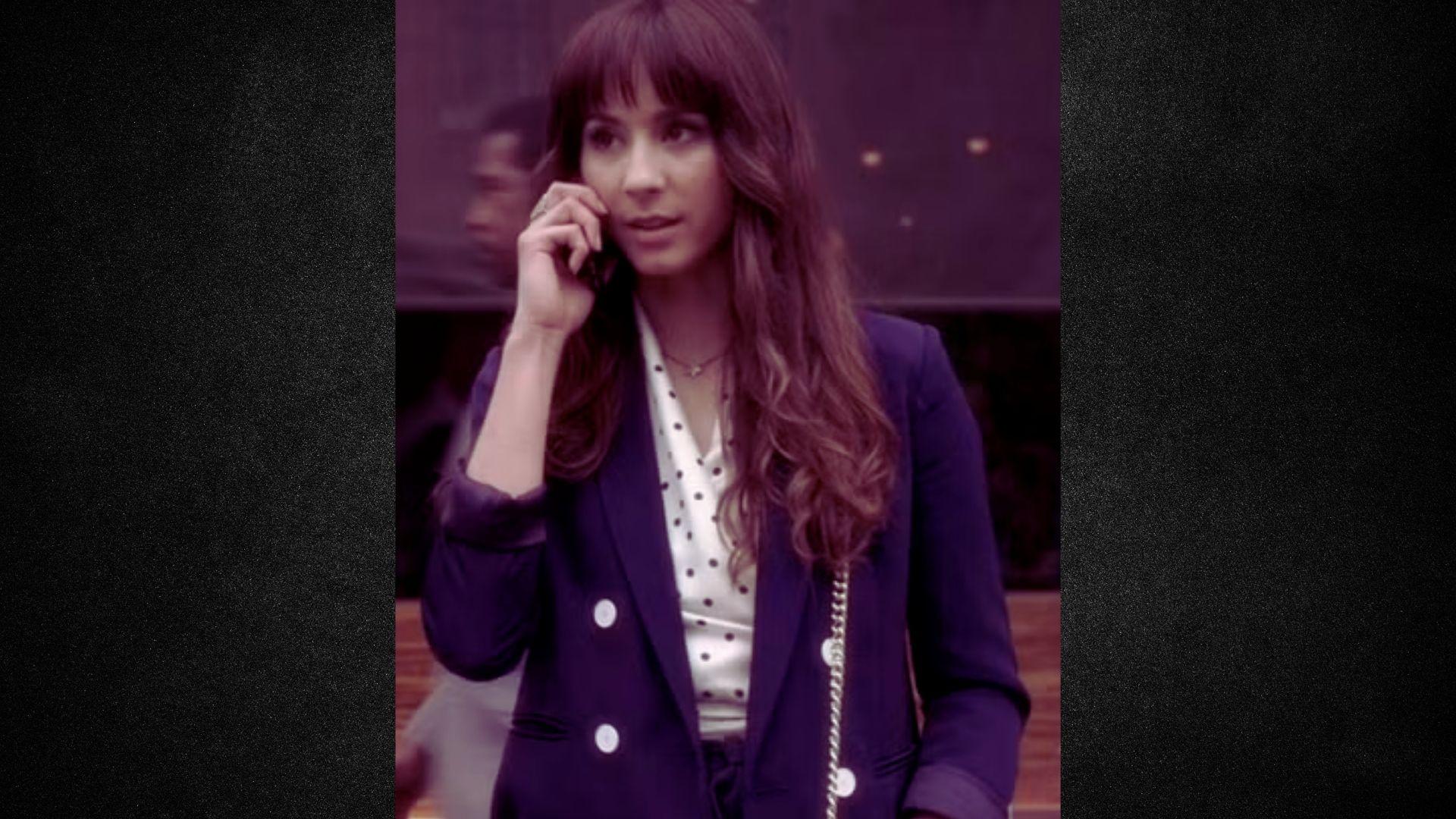 A woman dressed in a purple suit talks on her cell phone, appearing focused and professional.