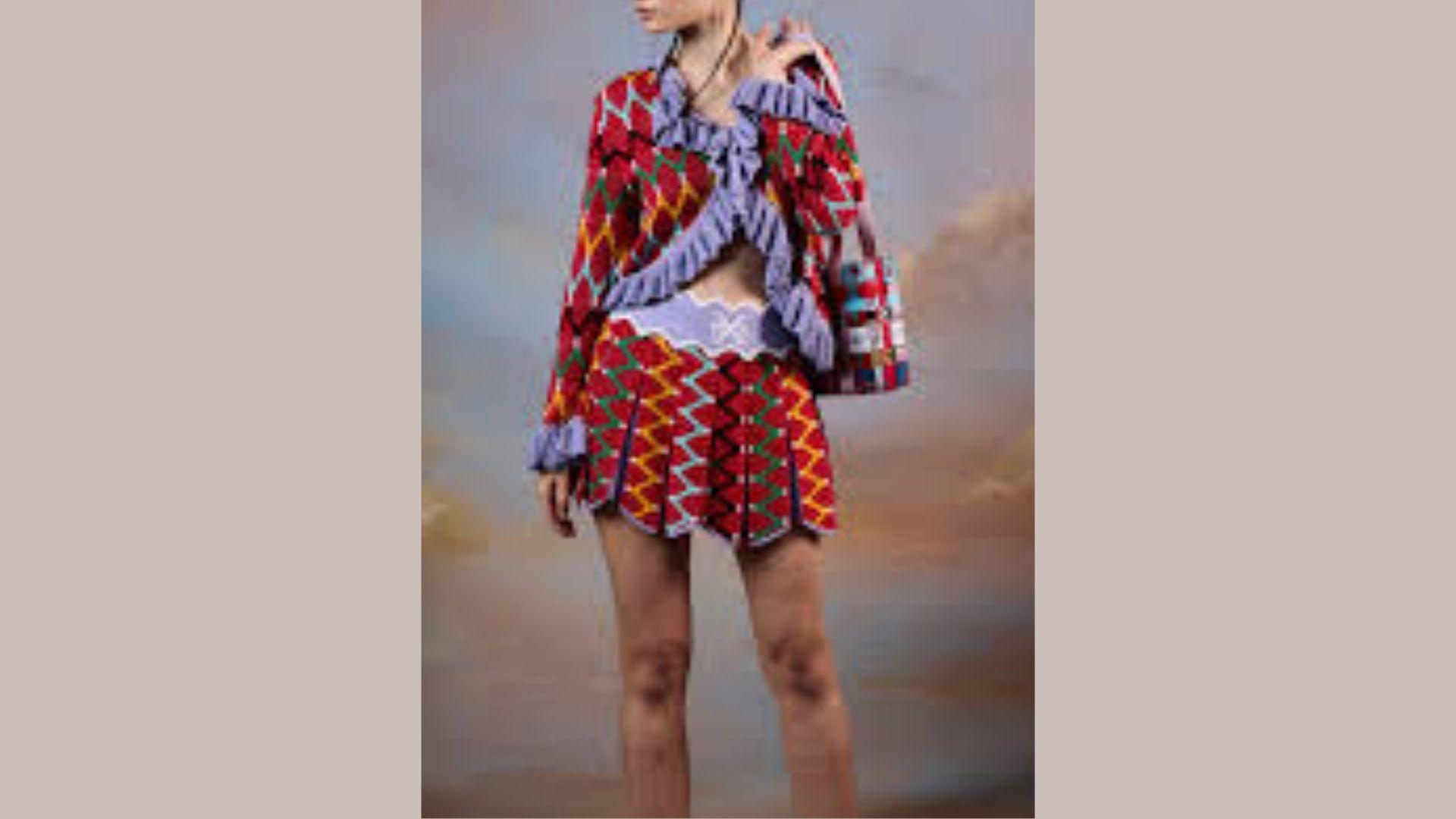 A model poses in a vibrant, colorful dress paired with a stylish jacket, showcasing a bold fashion statement.