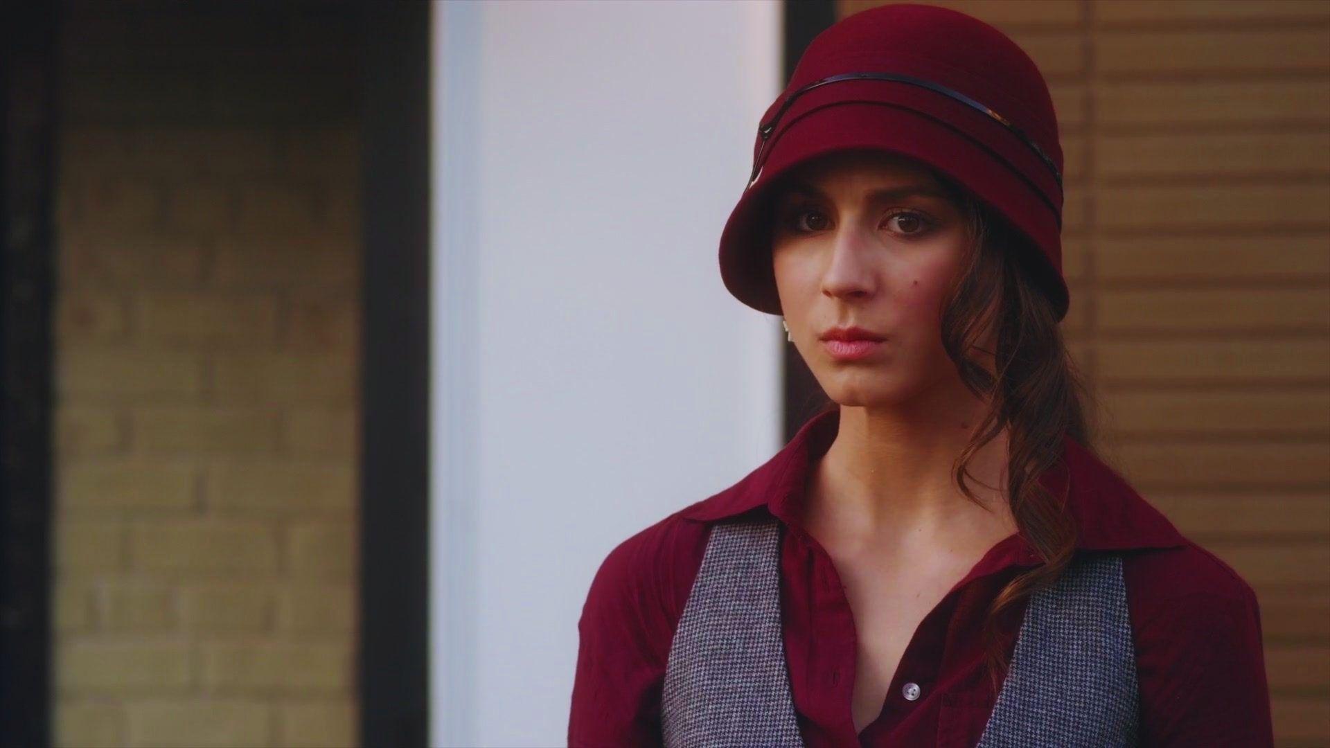 A woman wearing a bright red hat and matching vest, smiling and looking towards the camera.