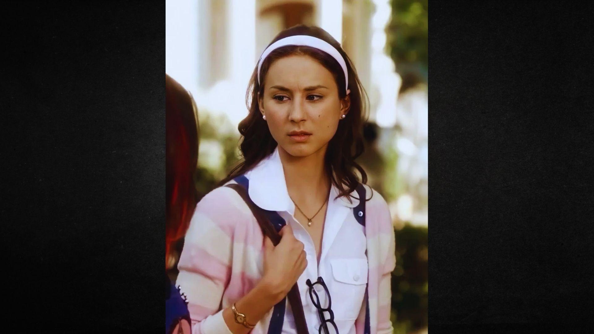 A woman with a white headband and pink shirt poses confidently for the photo.