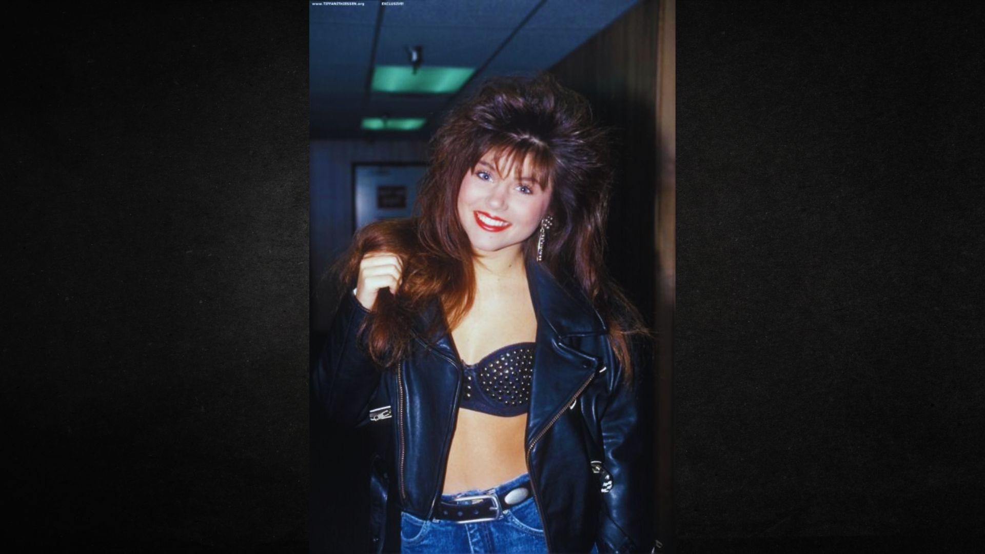 A woman in a leather jacket confidently poses for a photo, showcasing her stylish look and strong presence.
