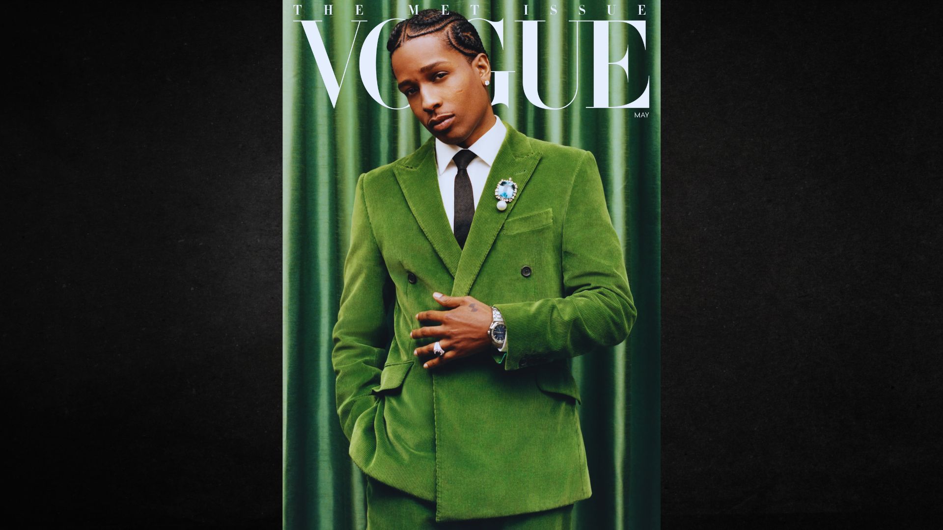 A man in a green suit poses confidently on the cover of Vogue magazine.