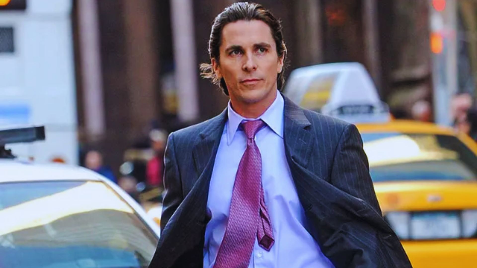 A man in a suit walks confidently on a city street, with taxis in the background. He exudes determination and focus, highlighted by his purposeful stride.