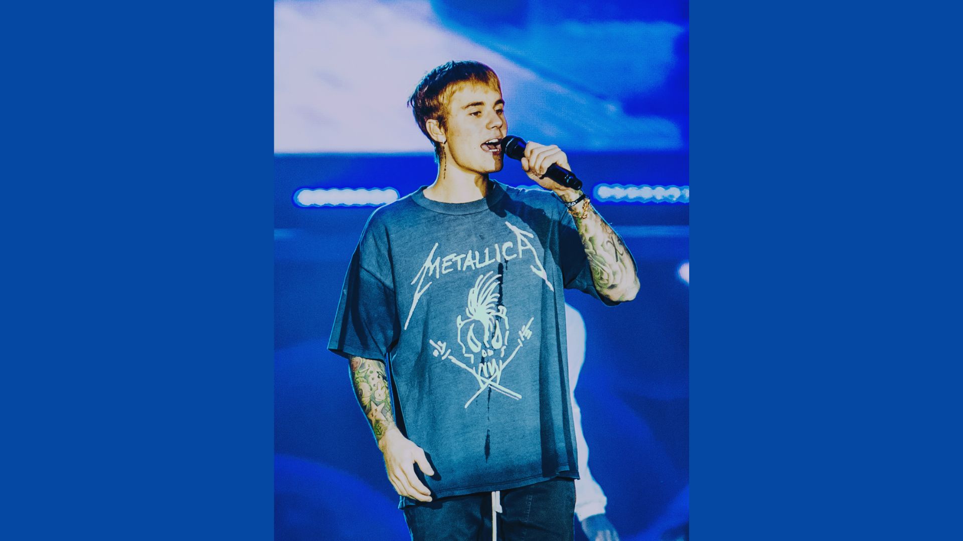 A man in a t-shirt stands with a microphone, preparing to address an audience.