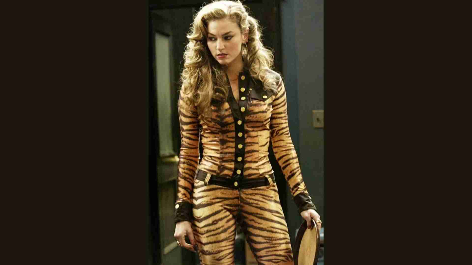 A woman wearing tiger print clothing stands confidently in a stylish room.