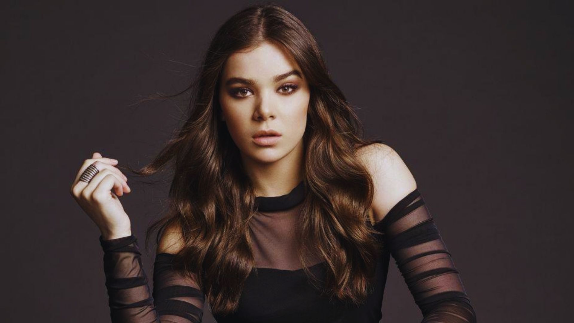 A woman wearing a sheer top over a black dress, showcasing a stylish and elegant look.