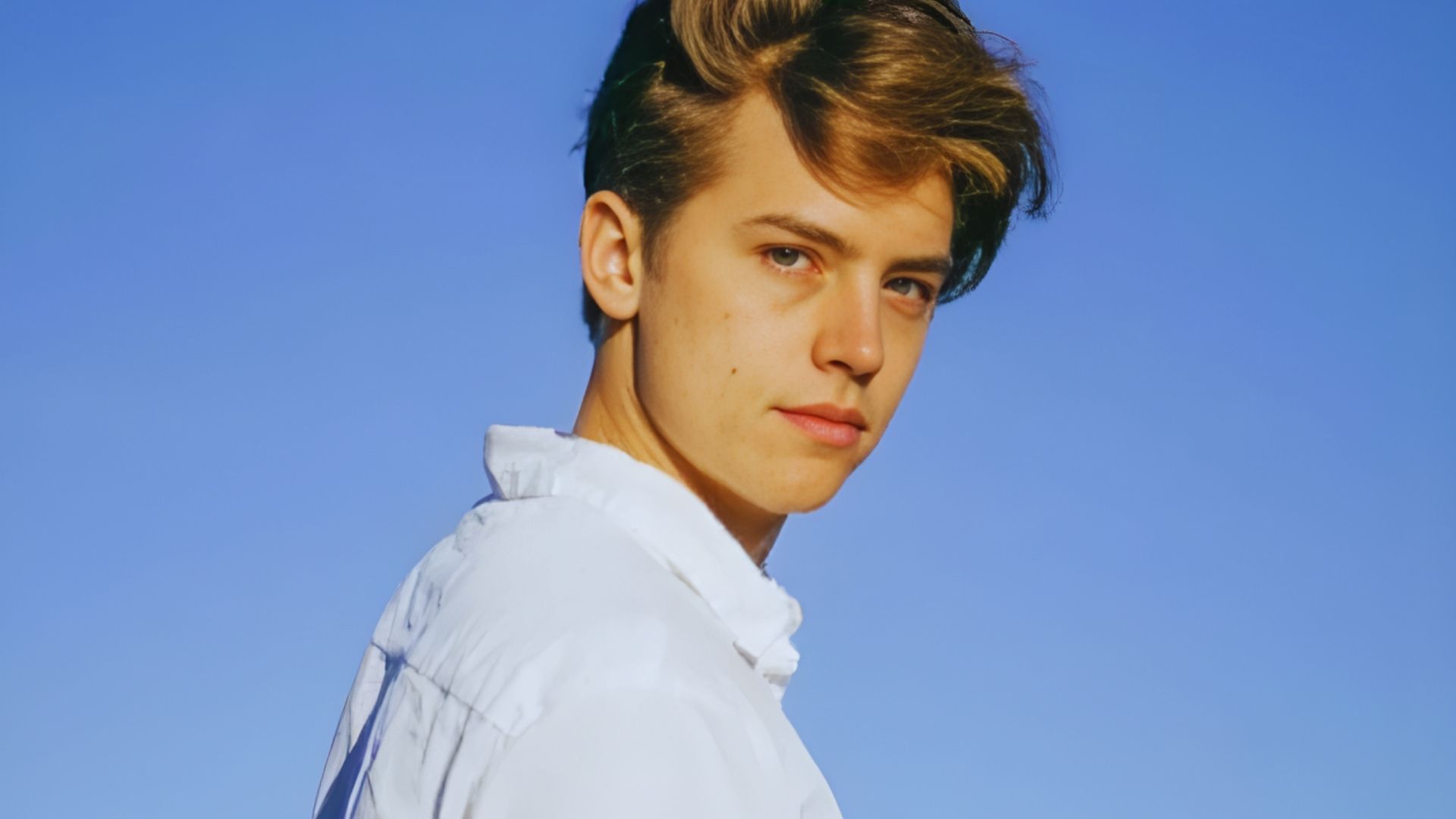 A young man in a white shirt stands against a clear blue sky, representing the theme "What Do Fans Actually Think."