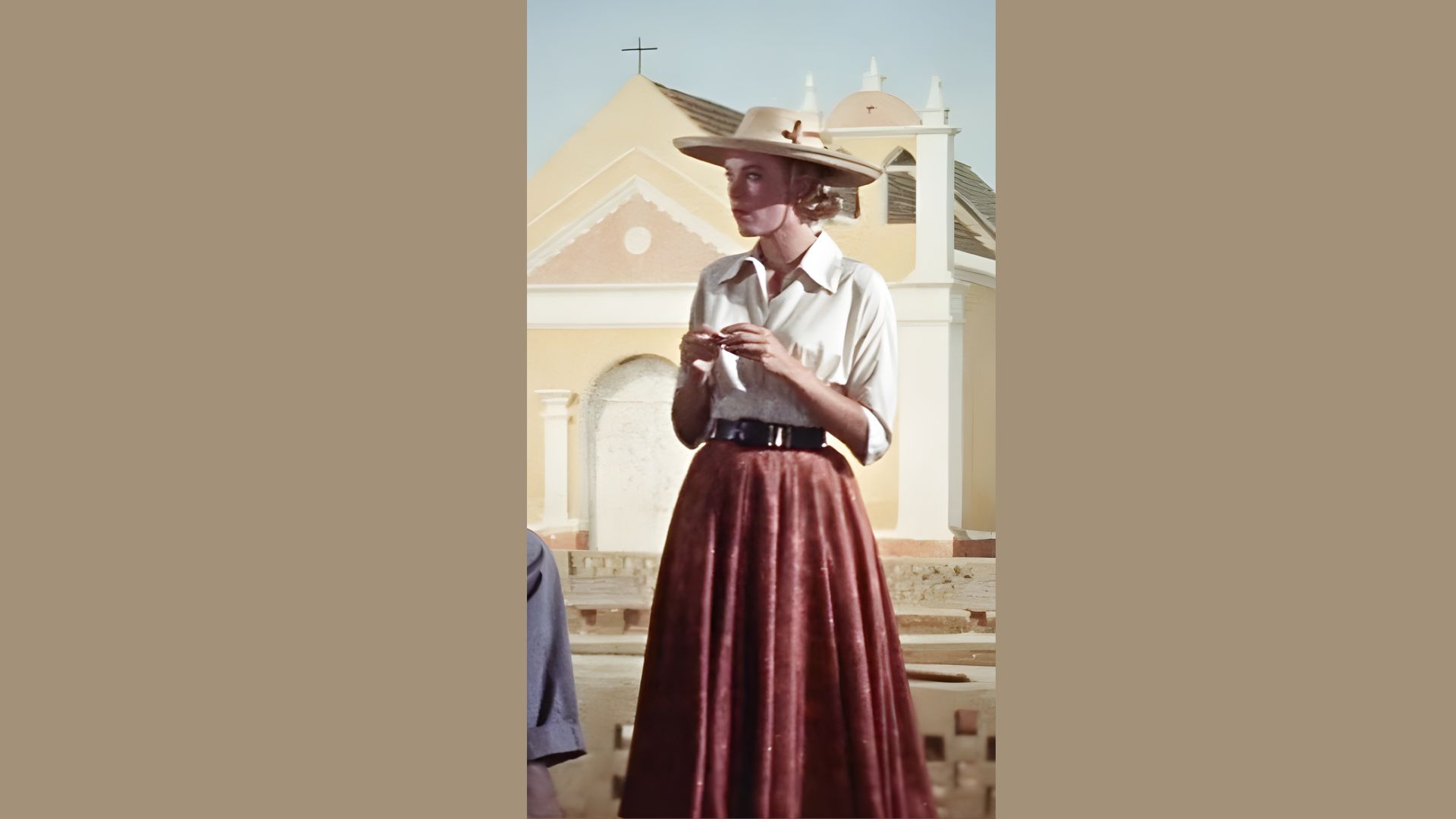 1. A woman in a hat and skirt stands beside a man, both smiling in a casual outdoor setting.
