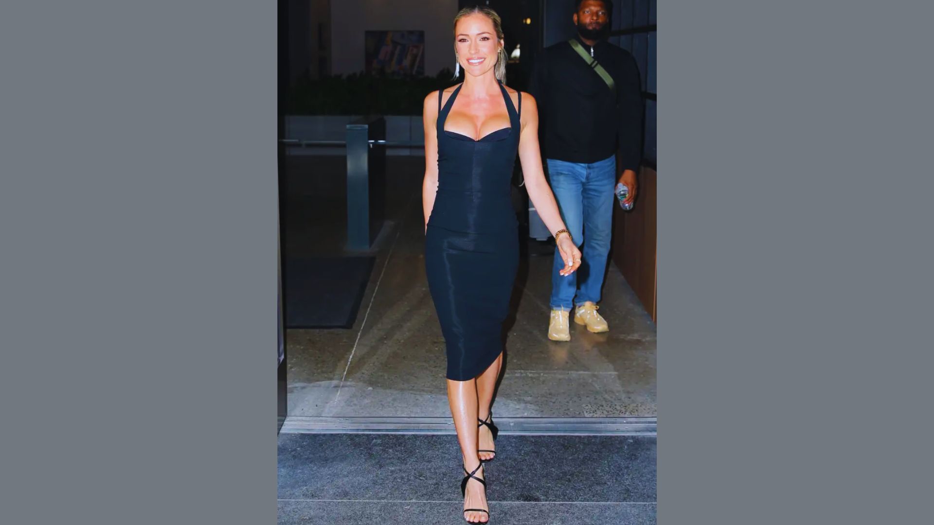 A person wearing a stylish black dress stands confidently, showcasing elegance and sophistication.