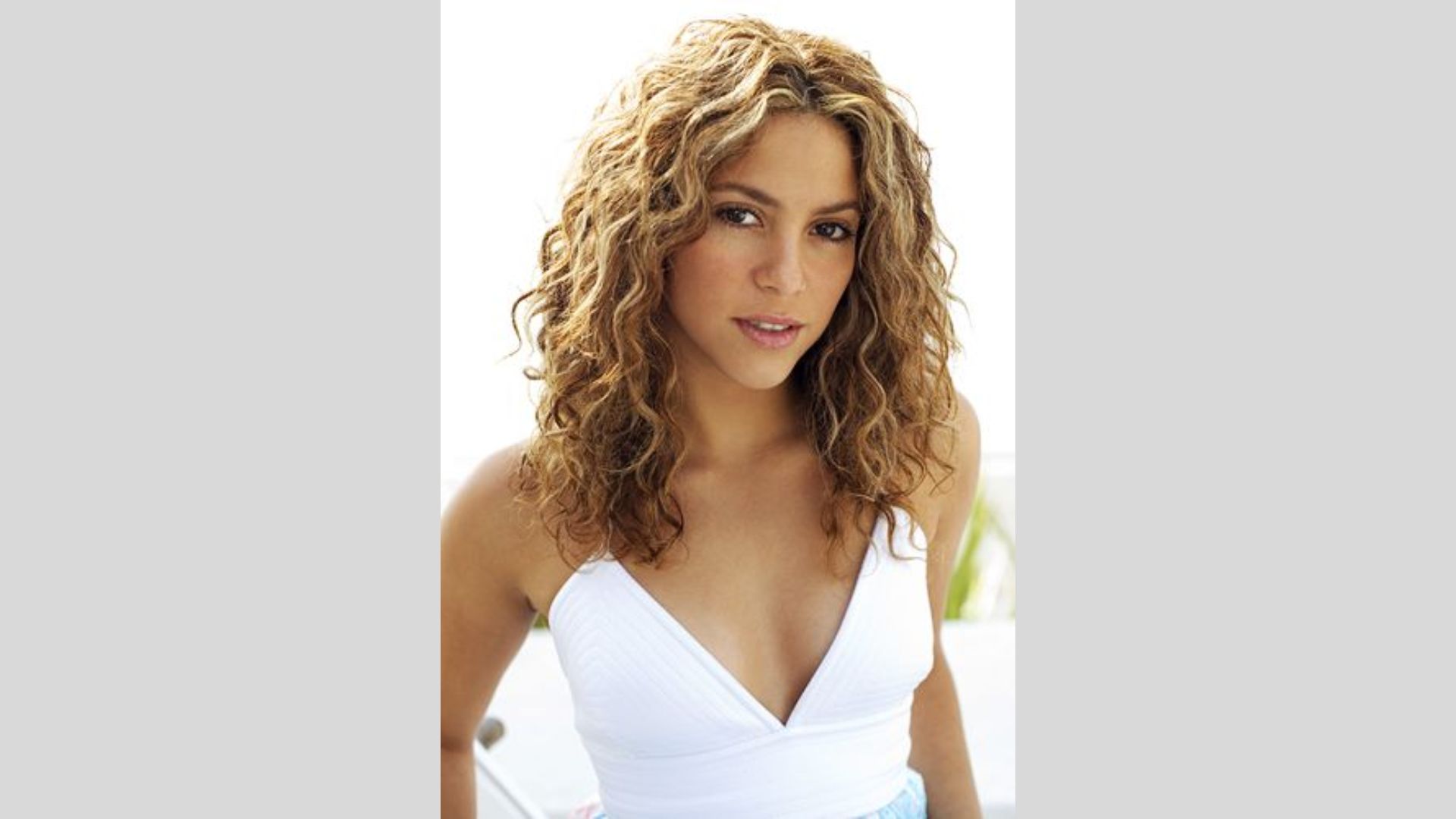 Shakira, with her short curly hair, strikes a pose for the camera, exuding charm and charisma.
