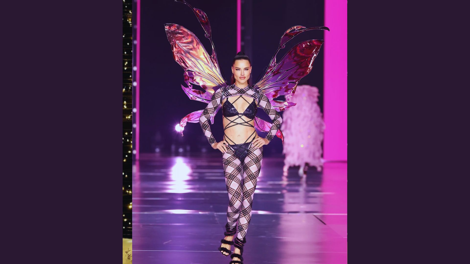 A woman models a vibrant butterfly costume on the runway, showcasing colorful wings and intricate details.