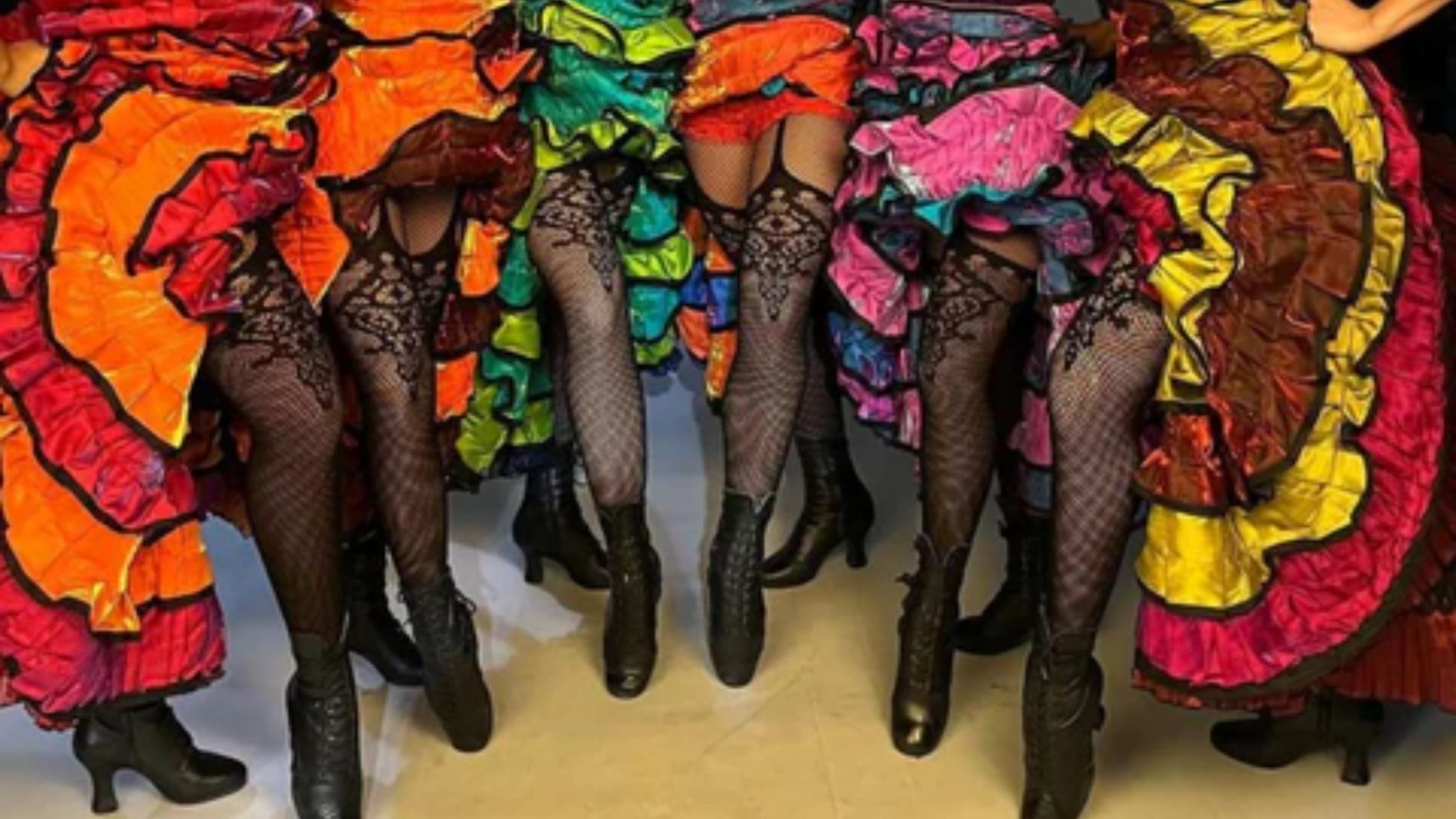 A group of women in vibrant costumes smiling and posing together for a photo.