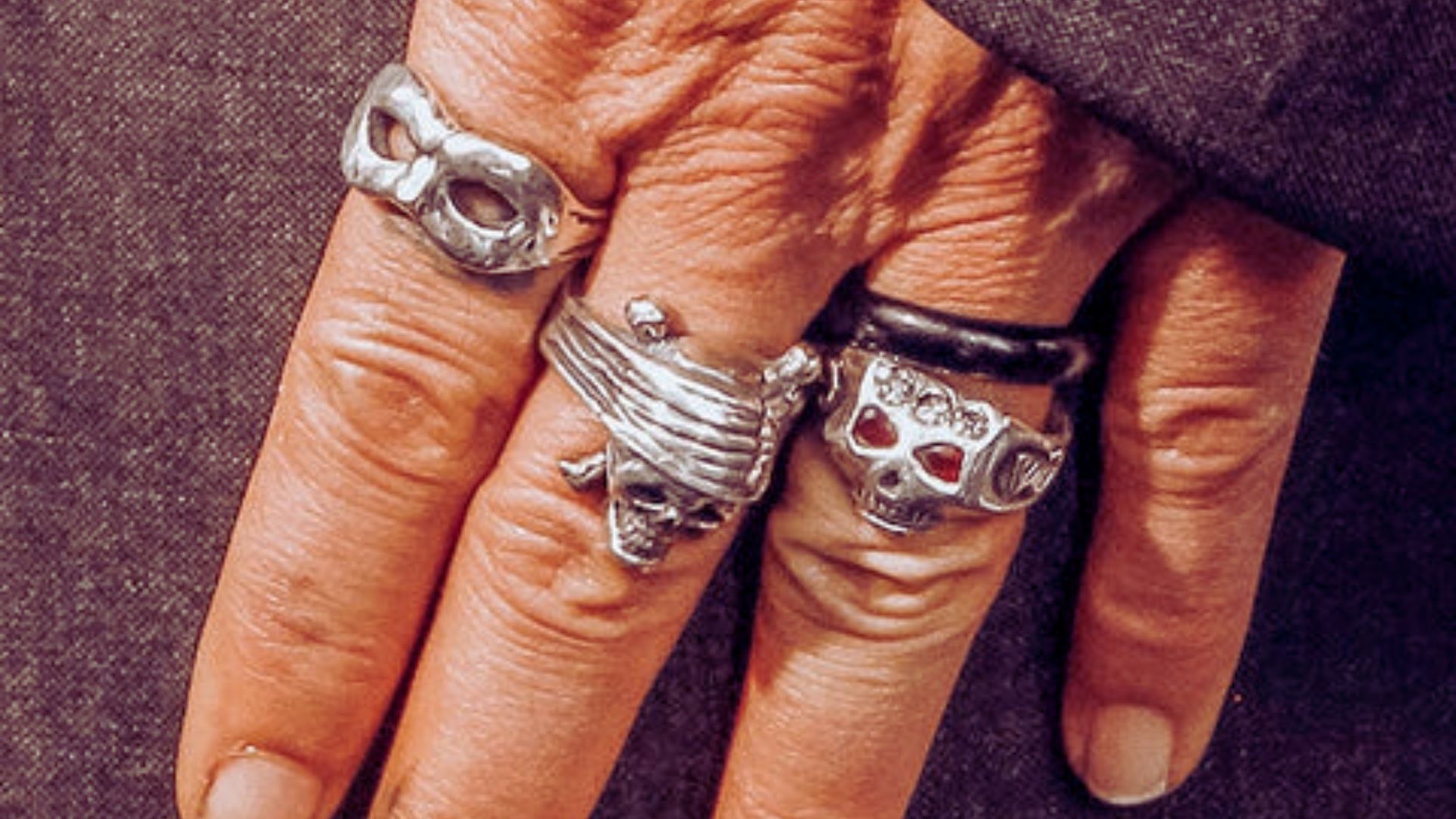 A person wearing a skull mask and a matching skull ring, creating a striking and edgy appearance.