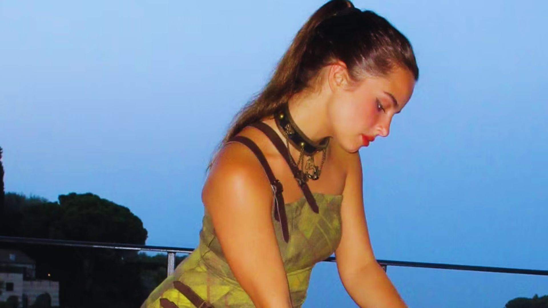A woman in a green dress plays a piano, showcasing her musical talent and elegance in a serene setting.