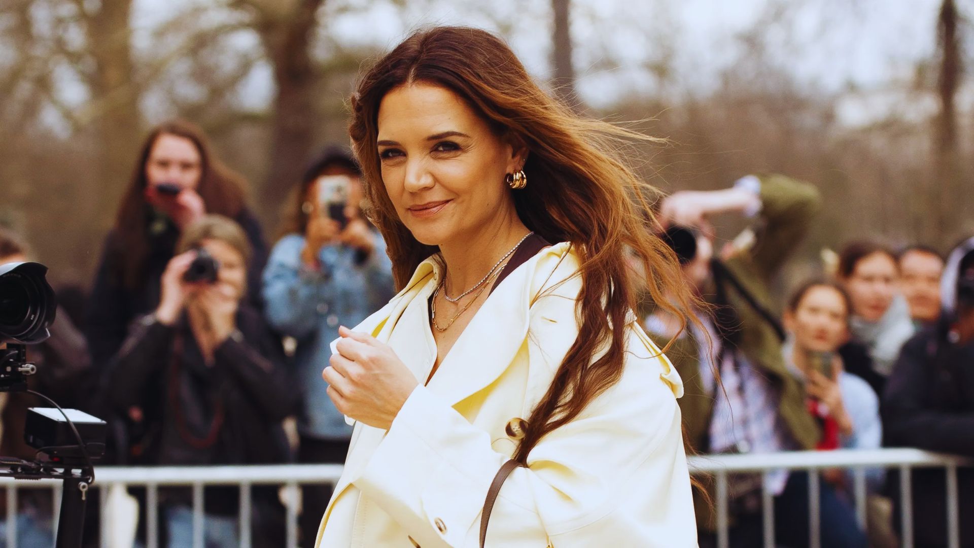 A woman in a white coat and black pants stands, representing a polished and professional look.