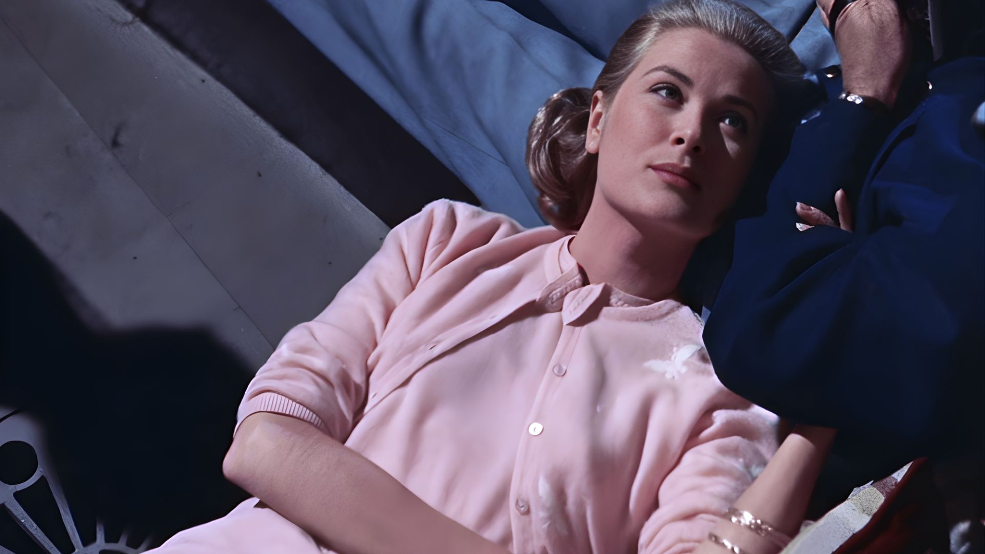 3. A woman in a pink dress is resting on a bed, exuding a sense of calm and leisure.