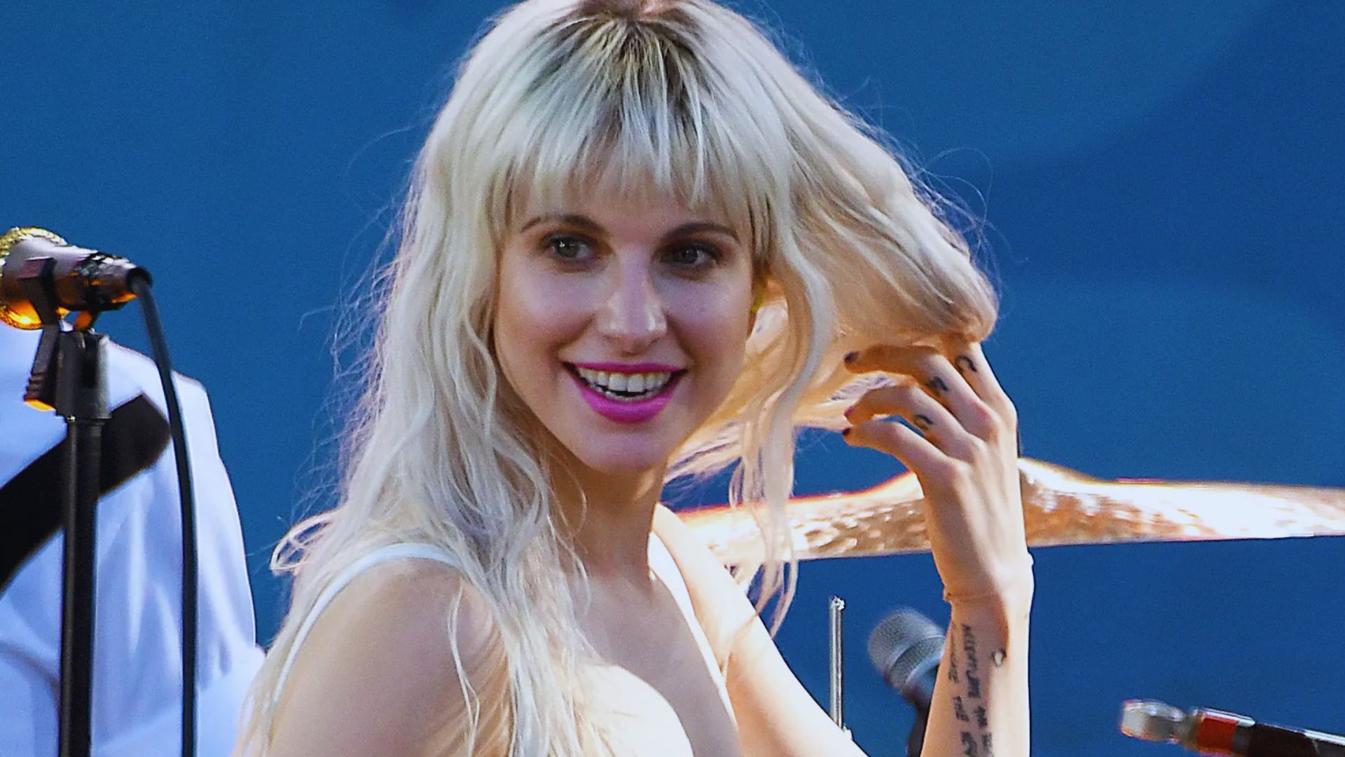 A woman with blonde hair poses with a guitar, showcasing her musical talent.