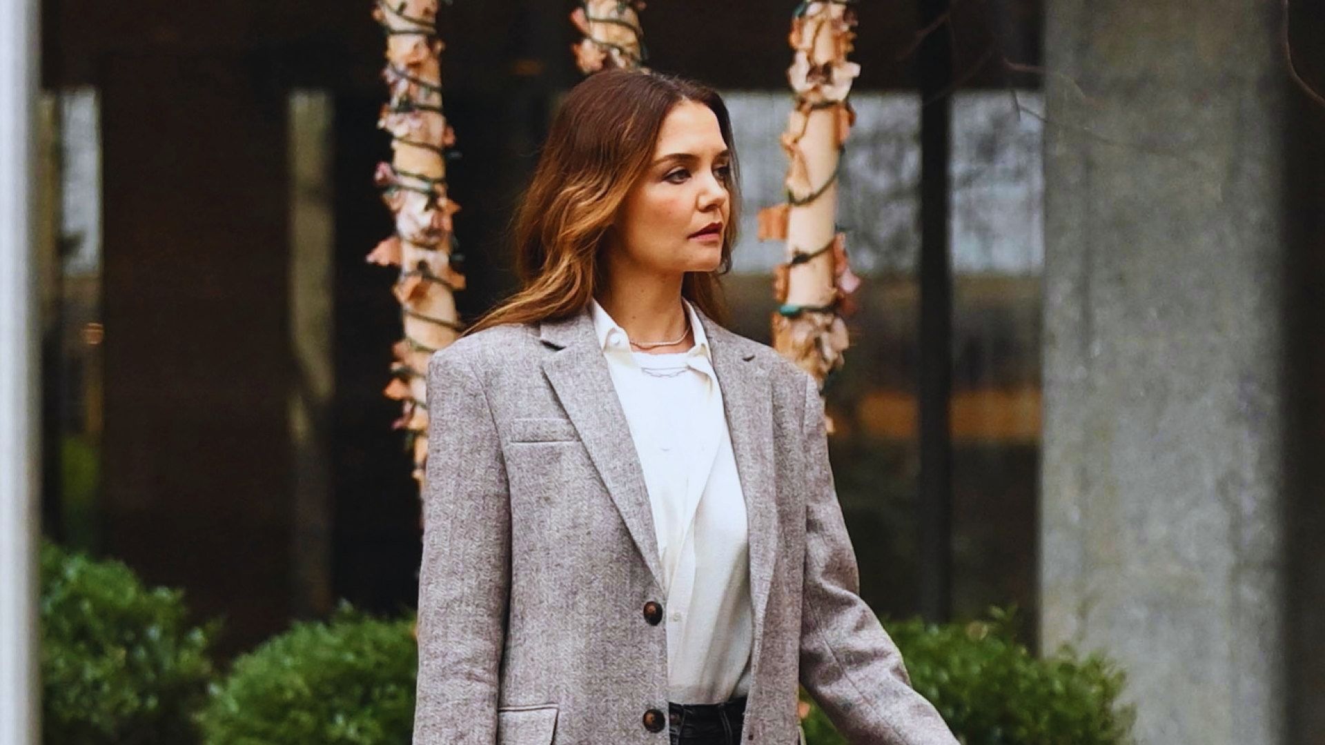 A woman in a tailored suit and white shirt walks purposefully down the street, embodying a professional demeanor.