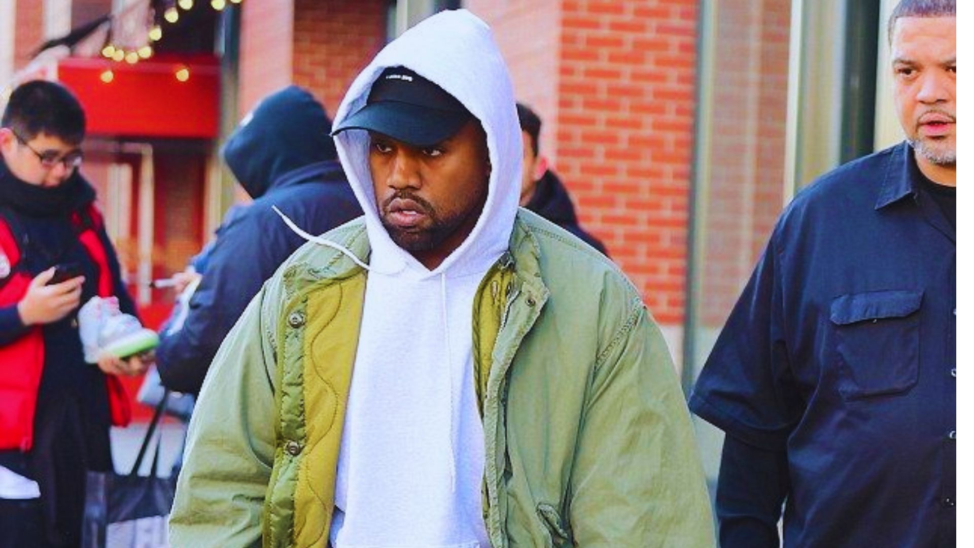 Kanye West is seen strolling on the street, dressed in a hoodie and jeans, embodying a relaxed, streetwear look.