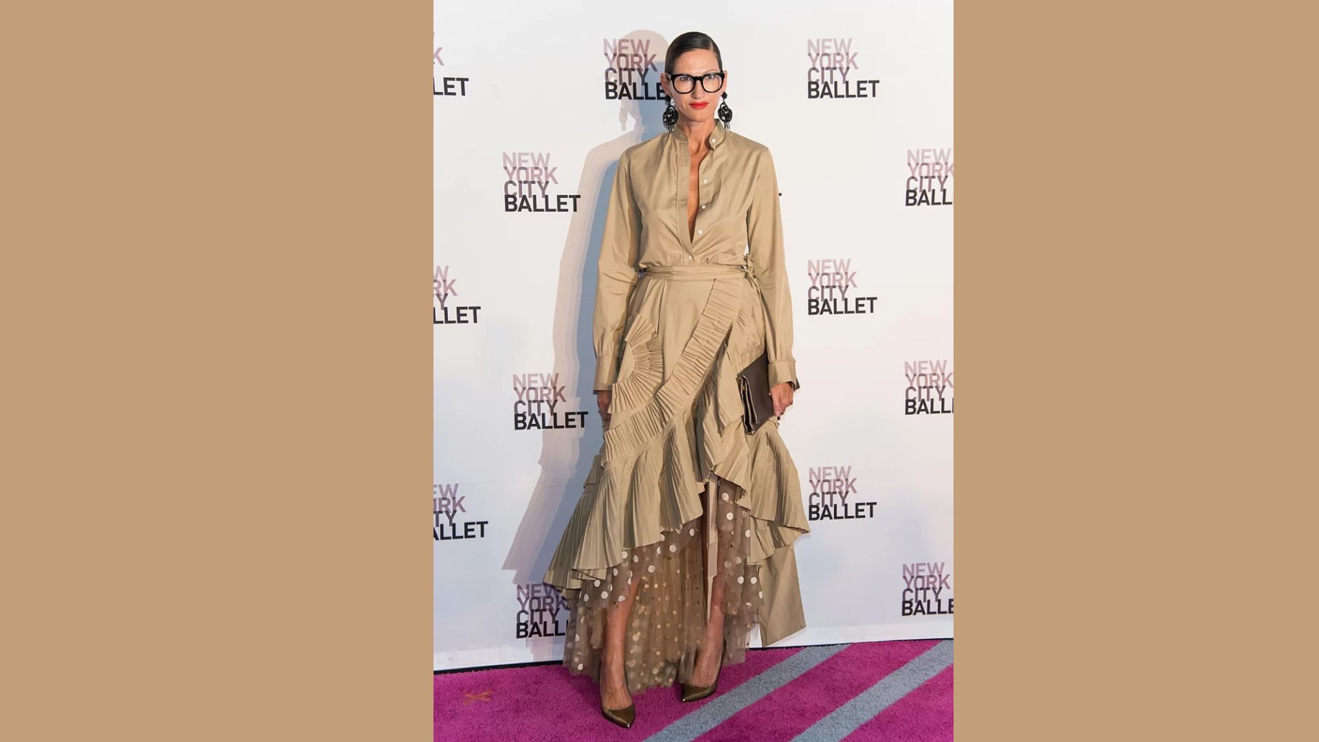 A person wearing a beige dress gracefully poses at a ballet ball, surrounded by elegant decor and soft lighting.