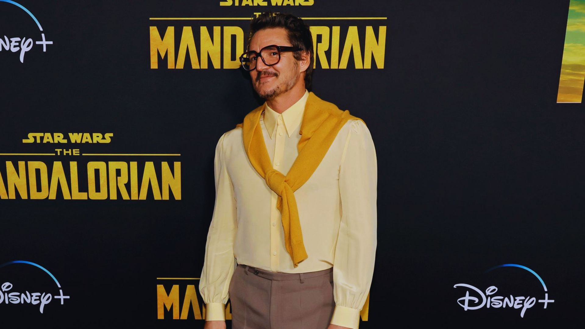 At the Star Wars premiere, a man in glasses and a yellow shirt stands, looking excited and engaged with the event.