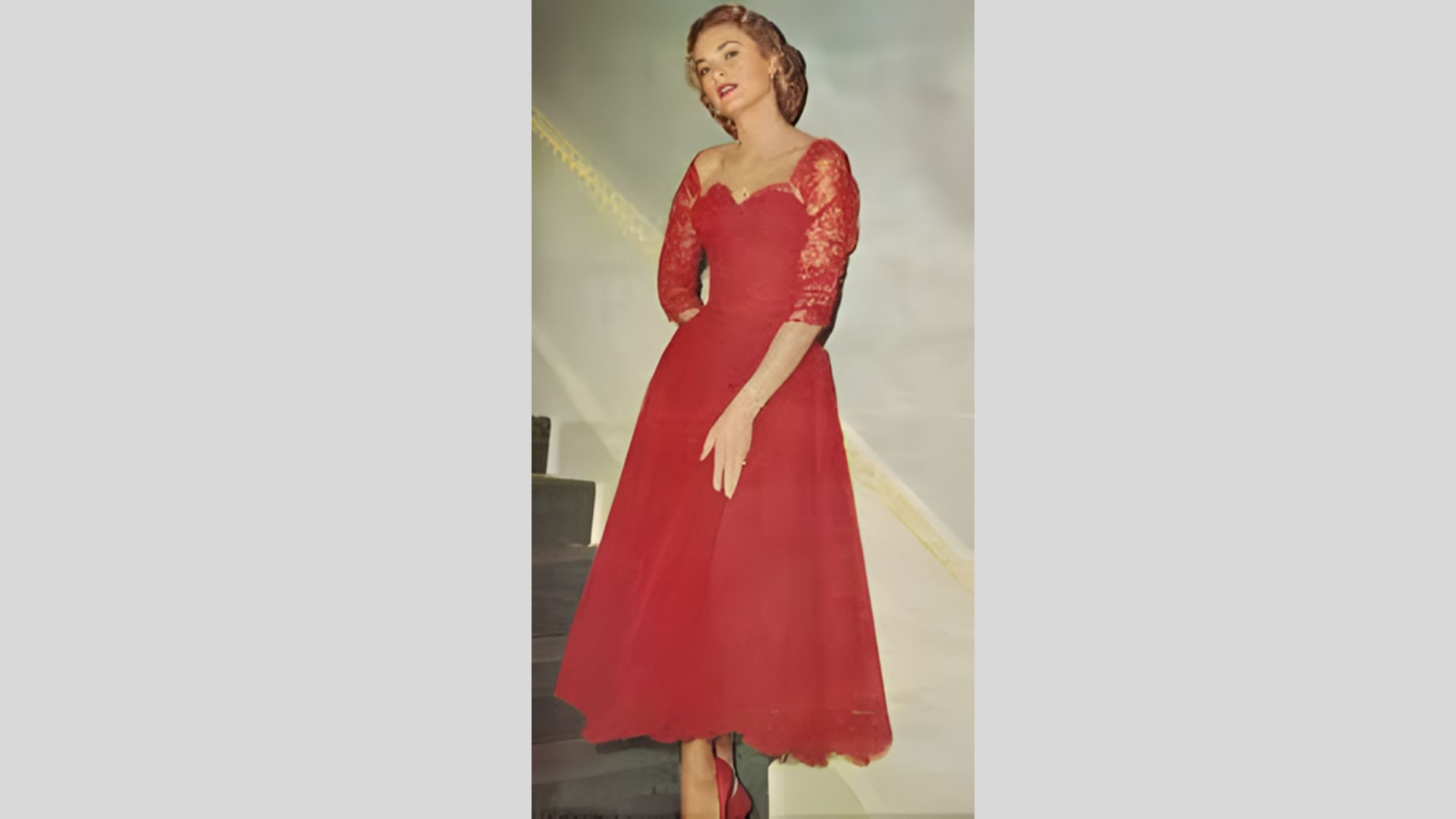 3. A woman in a vibrant red dress stands on stairs, exuding confidence and charm in her pose.