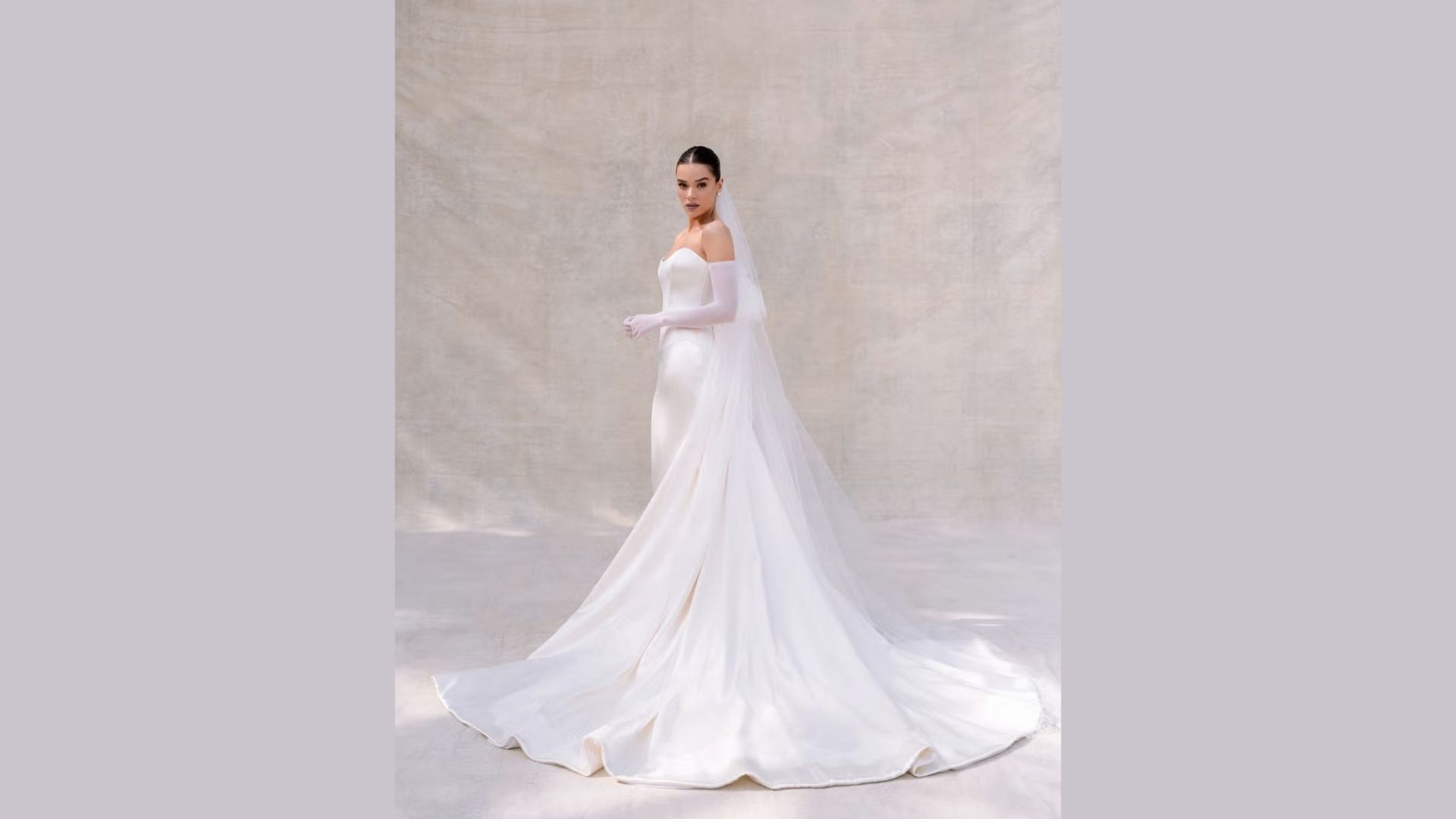 A woman in a bespoke double satin wedding dress poses elegantly for a photo, showcasing her corseted gown.
