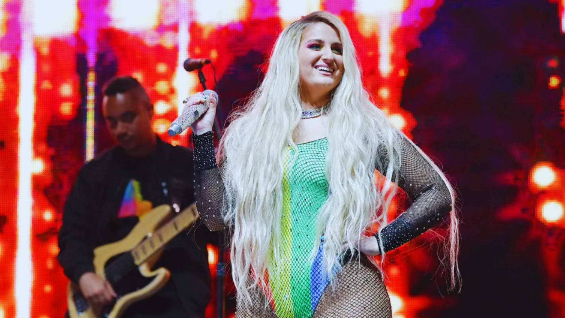 Meghan Trainor on stage wearing a sparkling multi-color dress.