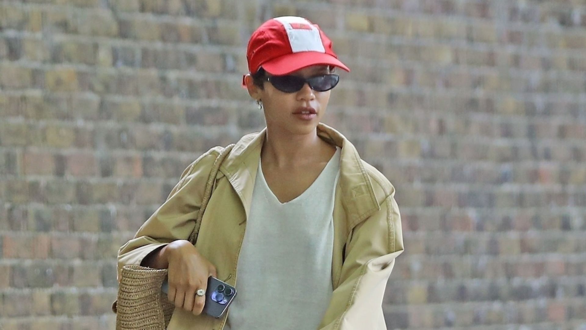 Taylor Russell walks down the street wearing a red hat and sunglasses, exuding a stylish and confident demeanor.