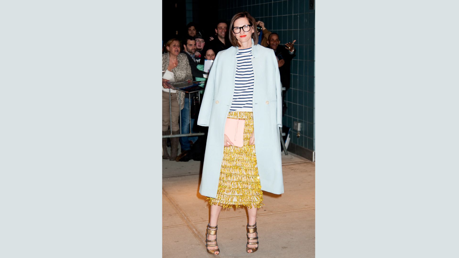 A woman in a yellow skirt and coat smiles, embodying a cheerful and fashionable look in her colorful attire.
