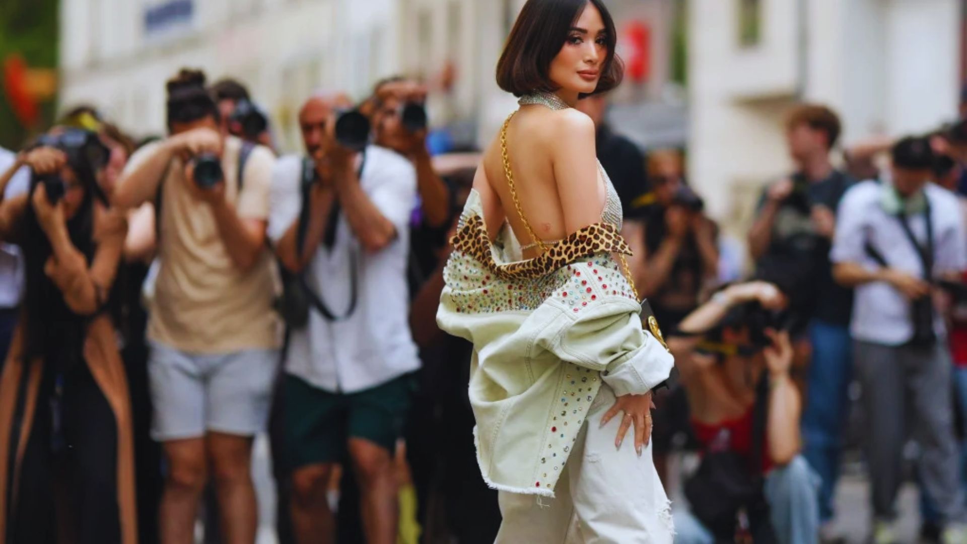 Heart Evangelista in white pants and a leopard print top walks confidently down the street, showcasing her stylish fashion sense.