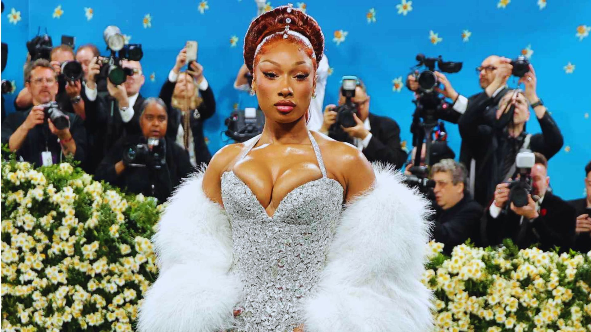 A woman wearing a white dress and a fur coat stands elegantly, showcasing a stylish winter outfit.