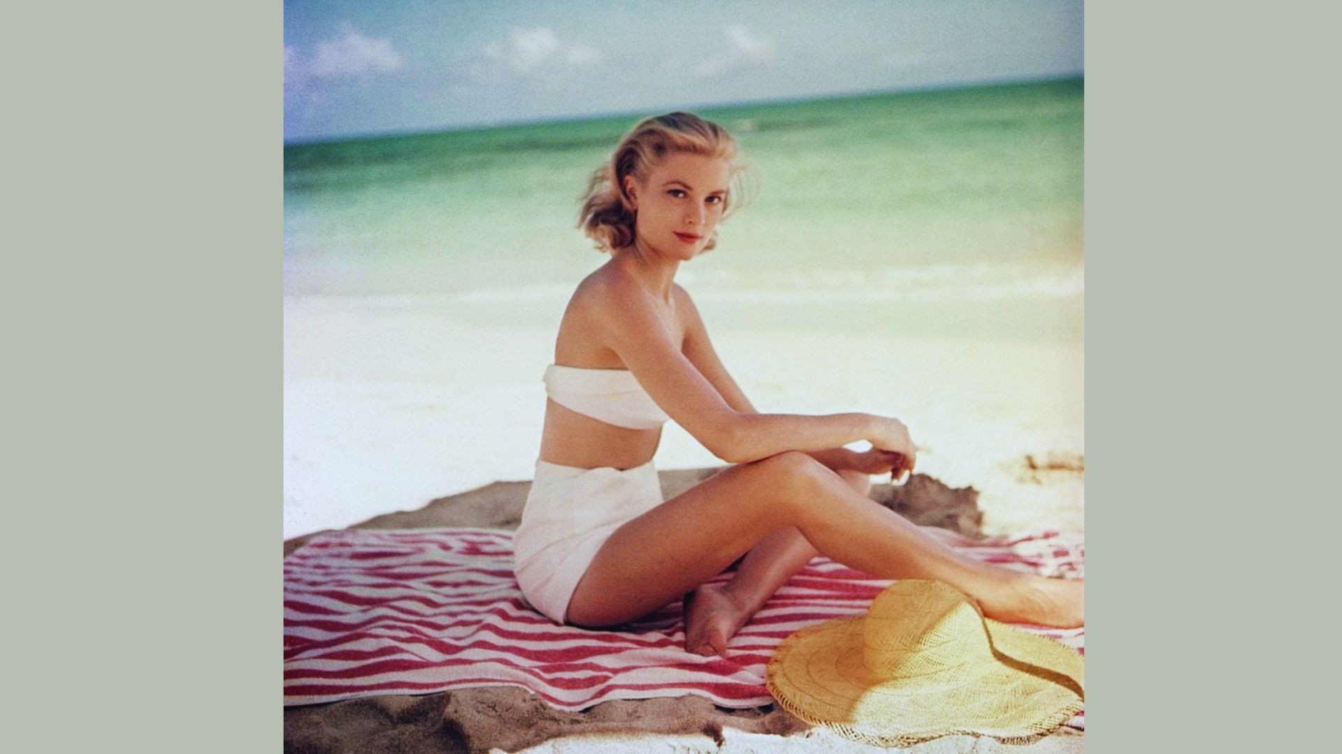 1. A woman in a bikini sits on a towel, enjoying the sun at the beach.