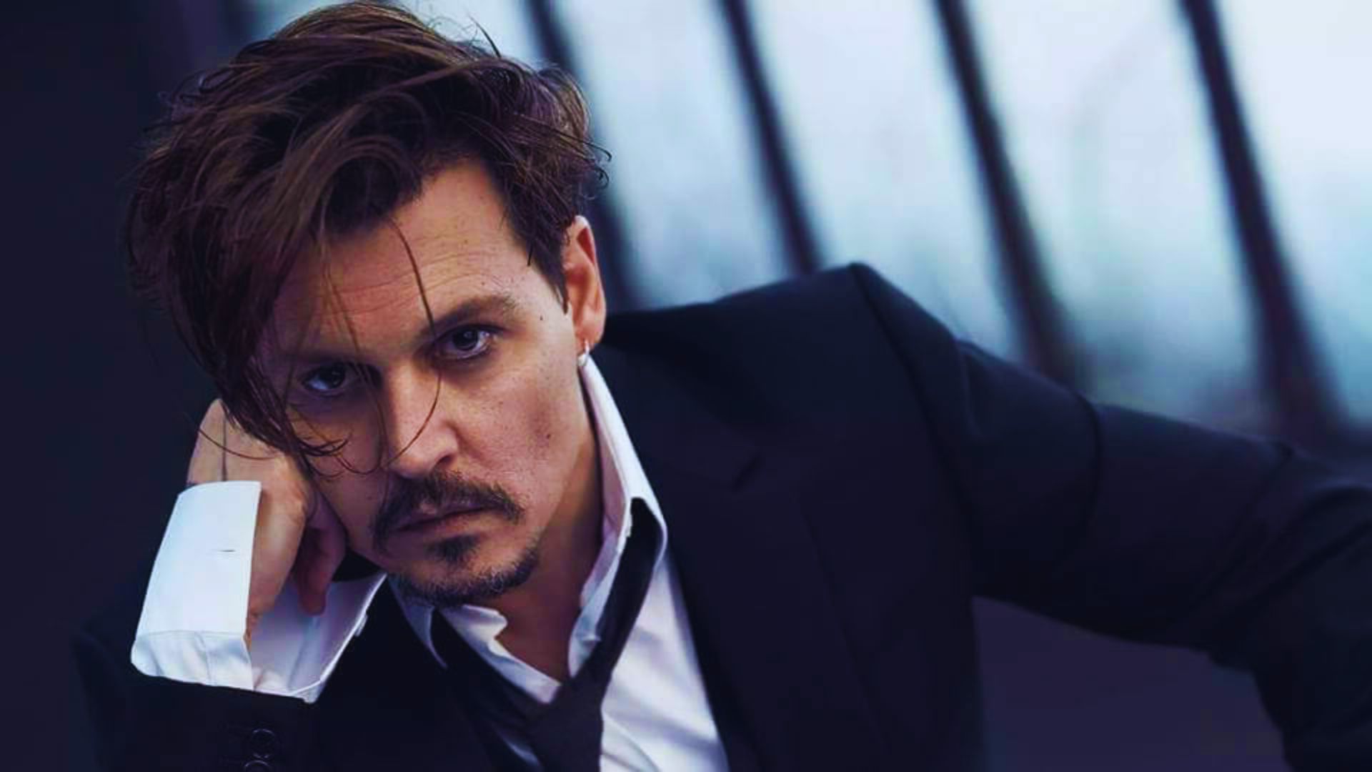 Johnny Depp wearing a formal suit and tie, looking sophisticated and stylish.