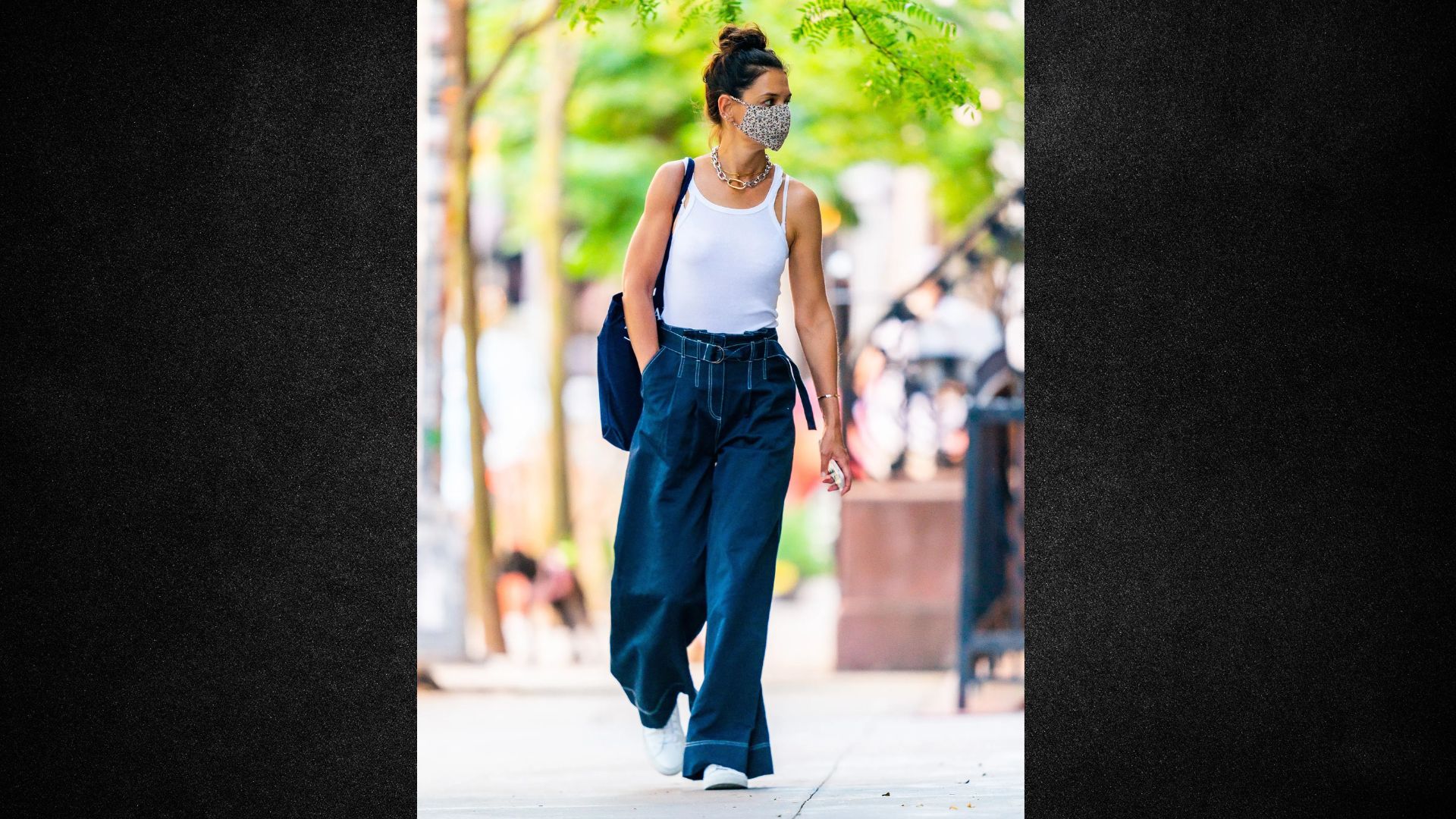 A woman in a white tank top and blue pants walks down the street, surrounded by urban scenery.