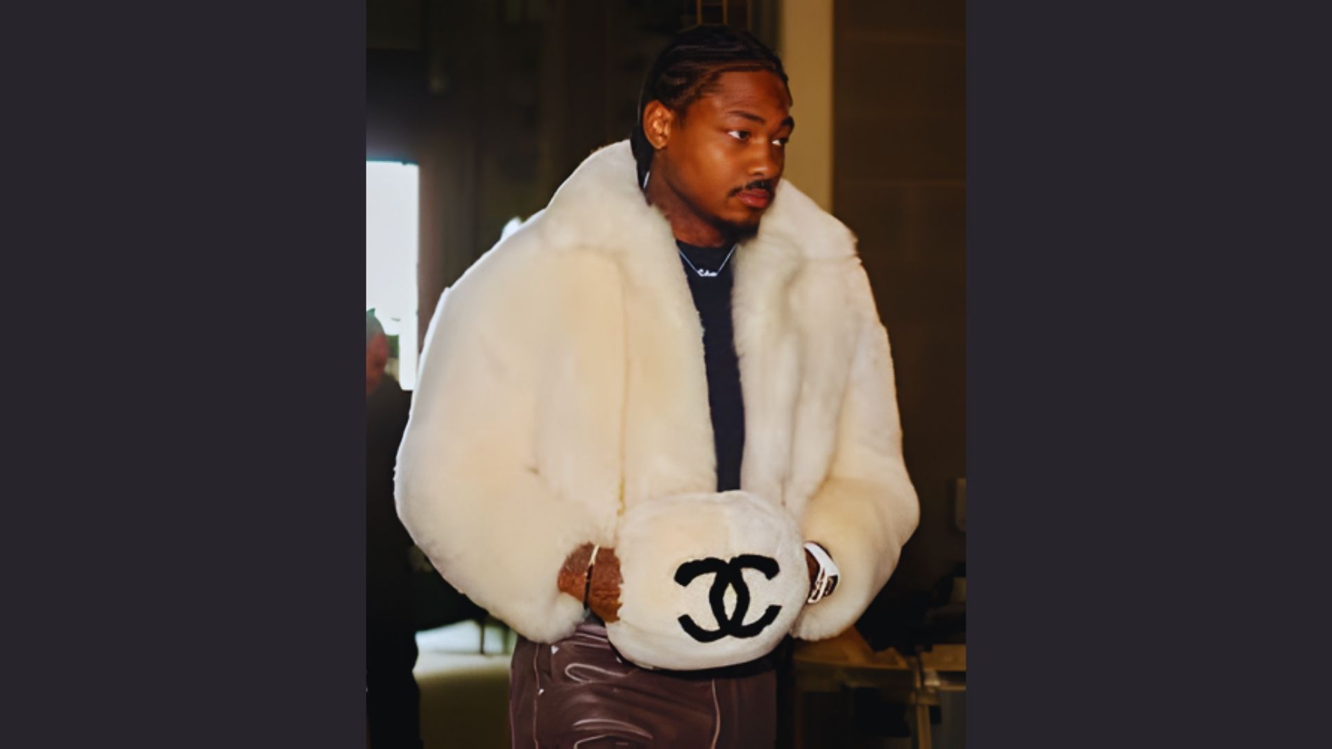 A man in a white fur coat holds a Chanel bag, showcasing a stylish and luxurious fashion statement.