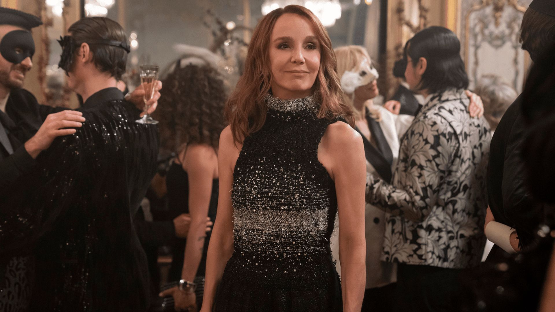 1. A woman in a black dress stands among a diverse crowd of people, engaged in conversation or observing the surroundings.