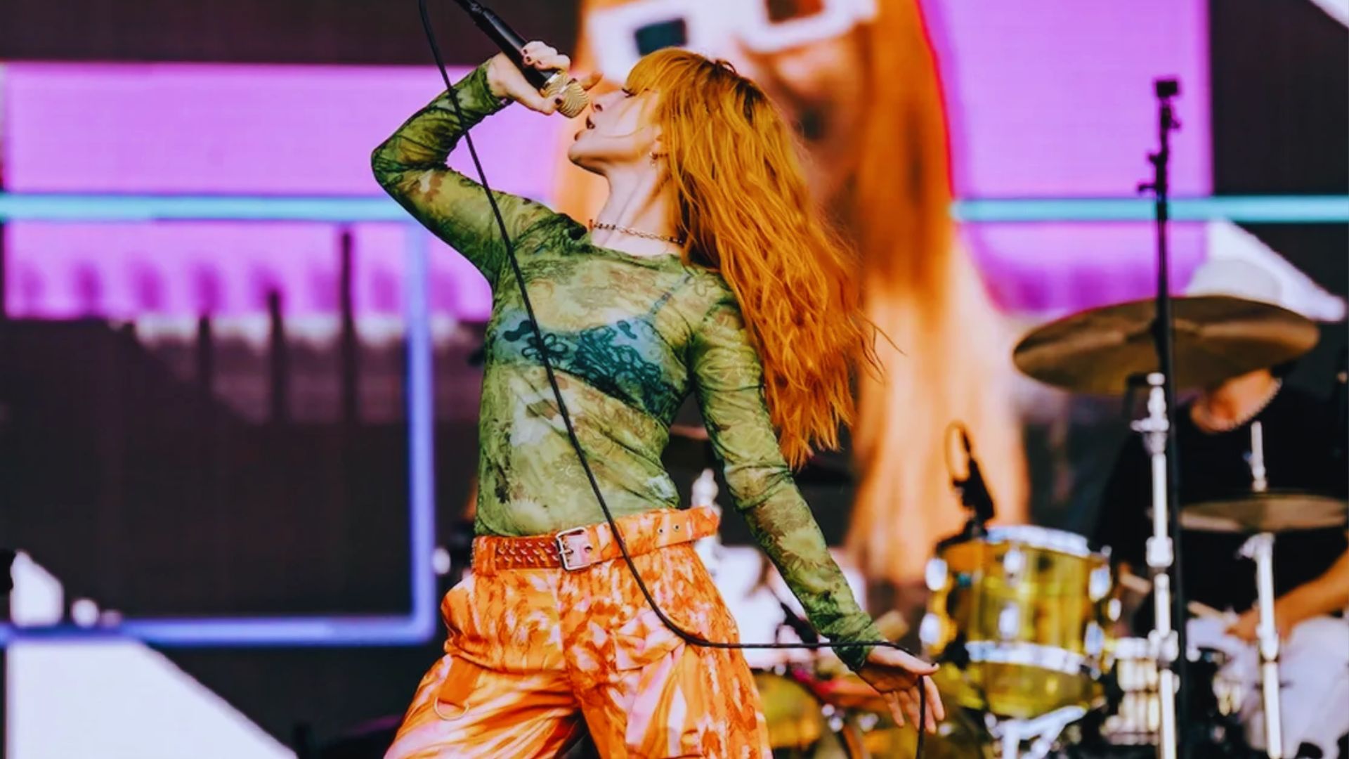 A red-haired woman performing a song on stage, engaging the audience with her voice.