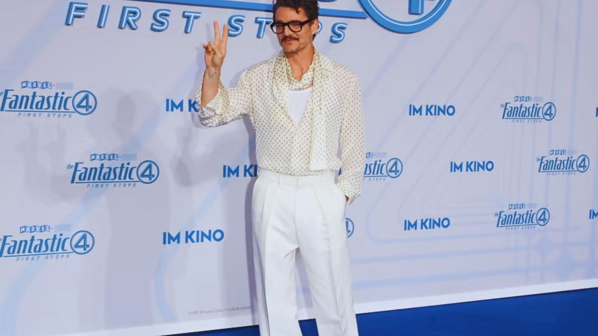 2. A man dressed in white pants and a white shirt stands confidently on a blue carpet, highlighting a modern aesthetic.