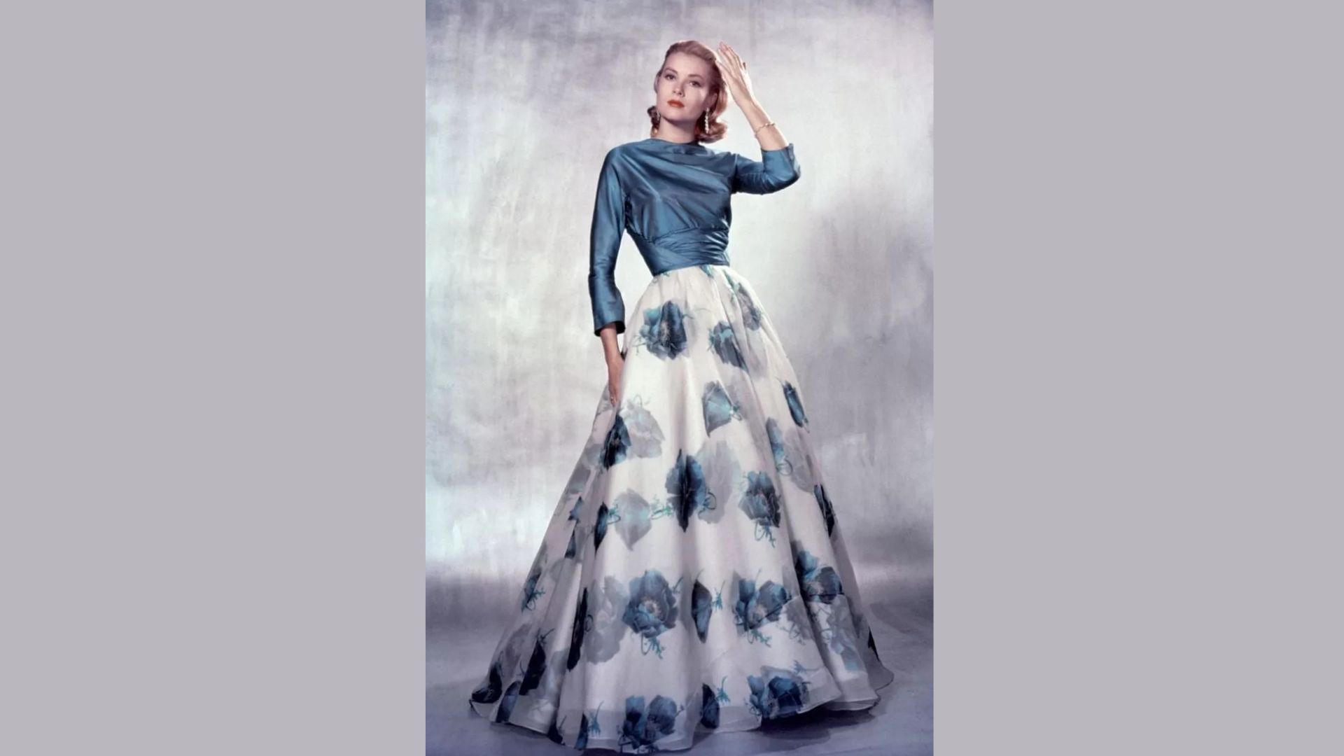 1. A woman wearing a blue and white dress stands gracefully, showcasing her elegant style.