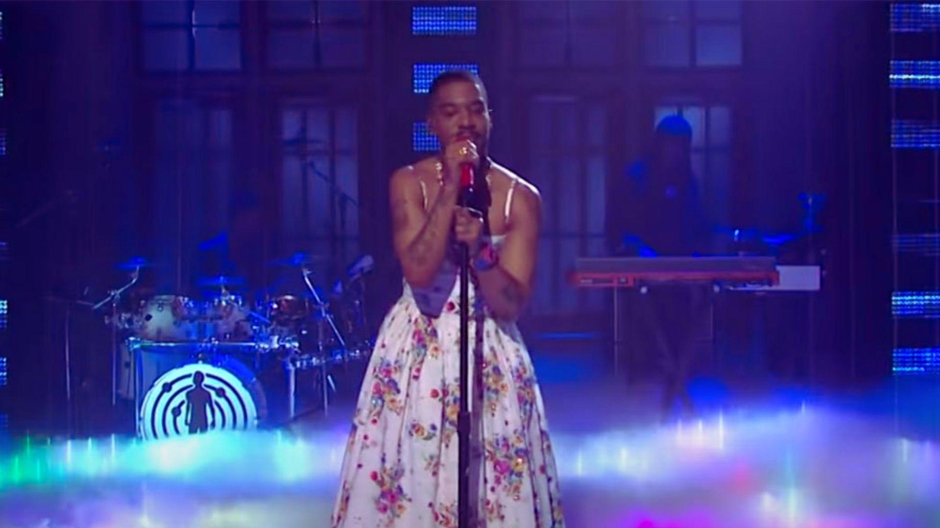 A woman in a floral dress passionately singing on stage, embodying the theme of breaking gender norms in hip-hop.