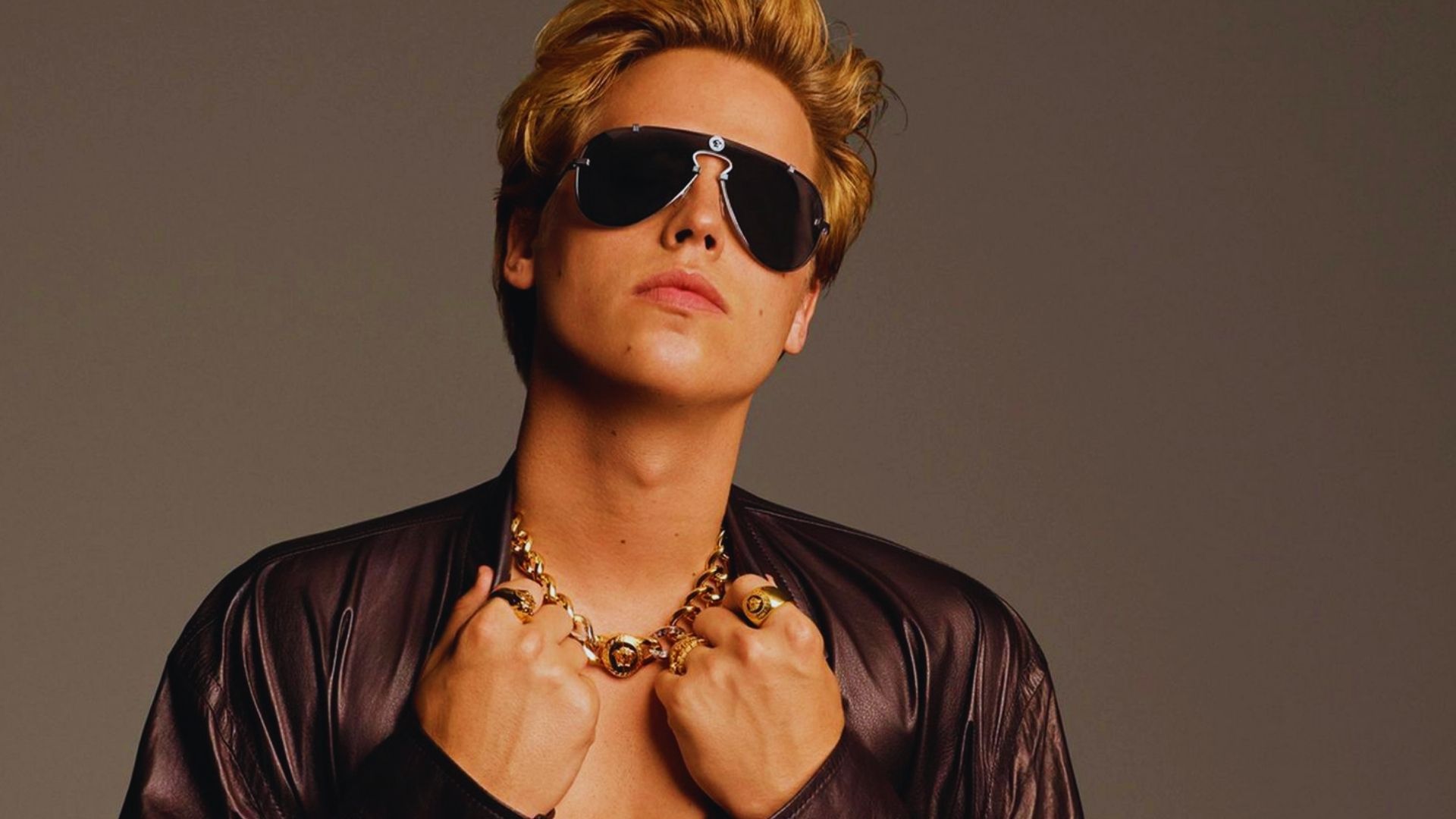 A man wearing sunglasses and a necklace, representing the style of 'The Blonde Comeback Era.'