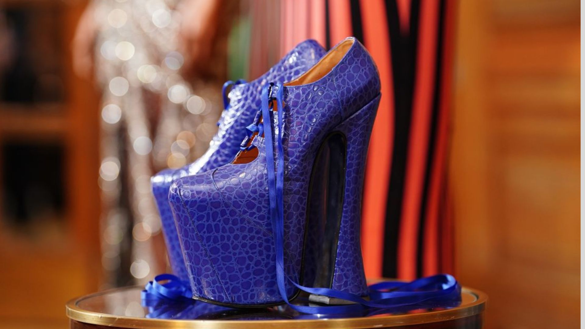A pair of blue Super Elevated Ghillie Platform high heels displayed on a table.
