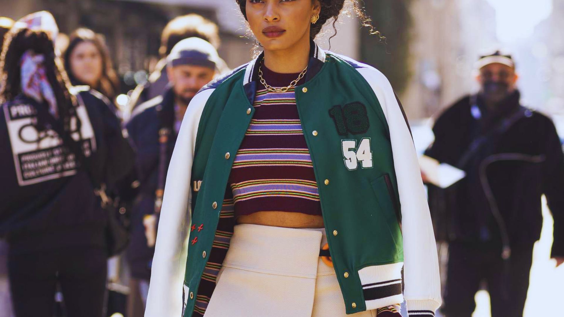 A woman wearing a green and white jacket paired with a matching skirt stands confidently.