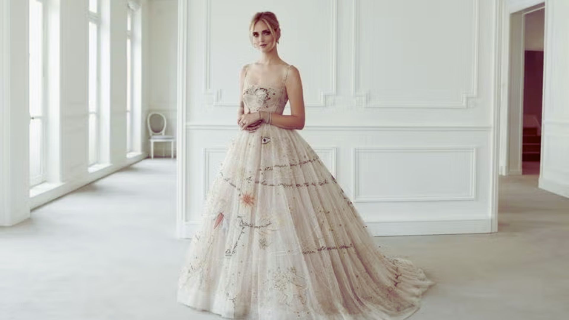 A woman in a wedding dress stands elegantly in a beautifully decorated room, radiating joy and anticipation.
