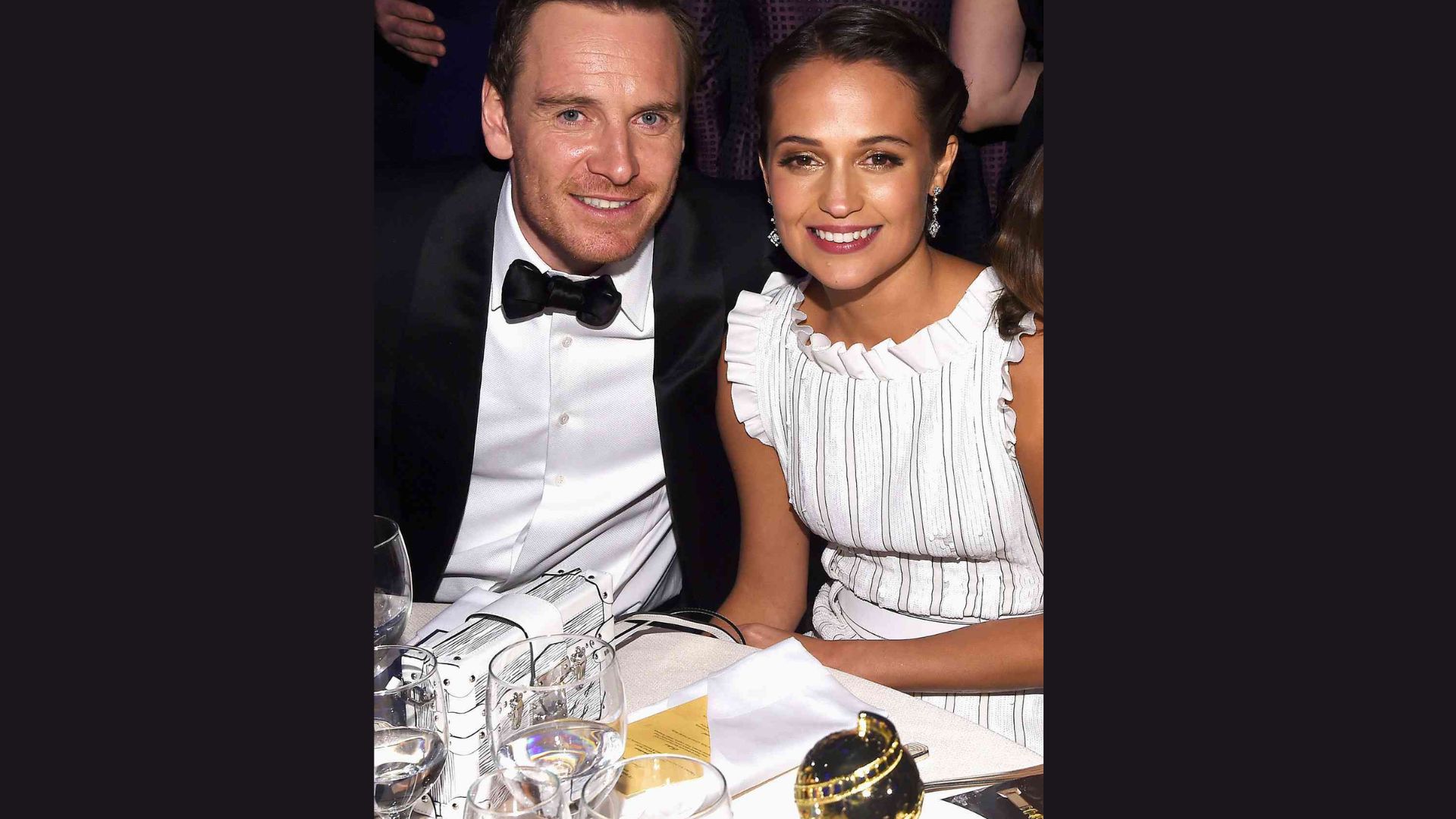 A man and woman seated at a dinner table, engaged in conversation over a meal.