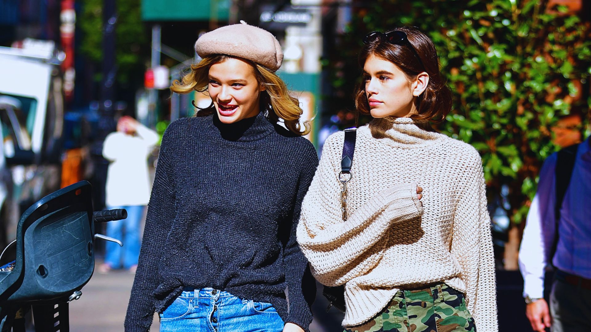 1. Two women in jeans and sweaters walking together down a city street.