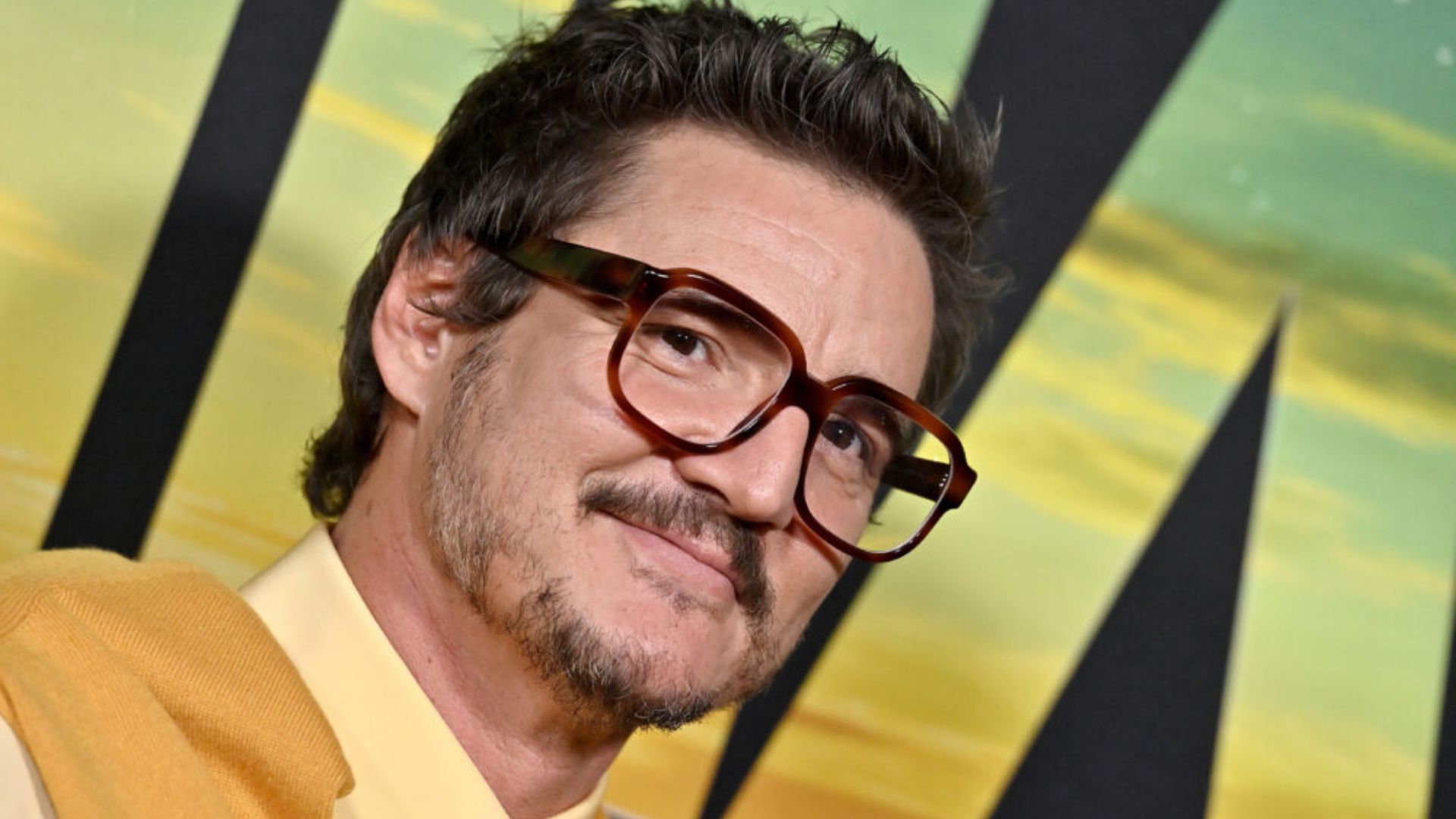 A man in a yellow shirt and glasses poses for the photo, showcasing a friendly expression.