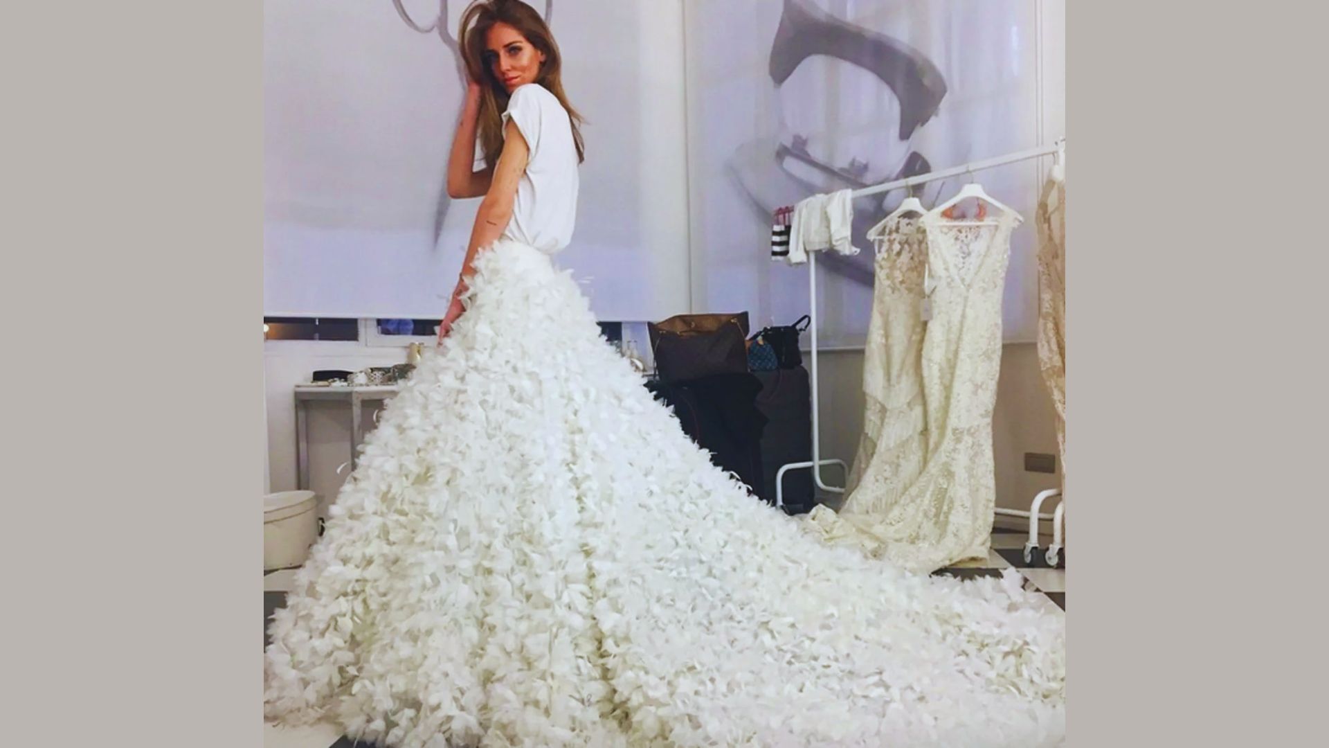 A woman in a wedding dress stands gracefully in front of a mirror, admiring her reflection.