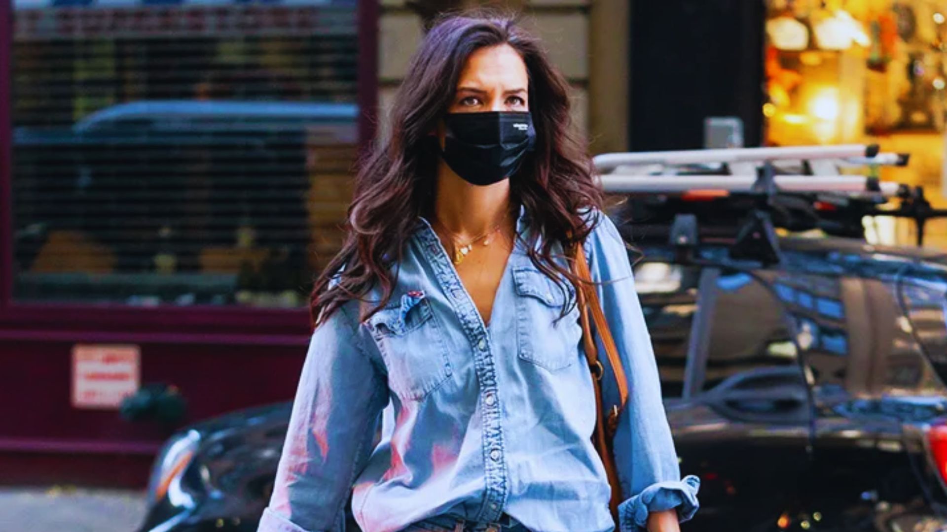 A woman wearing a face mask walks along the street, highlighting public health measures in urban settings.